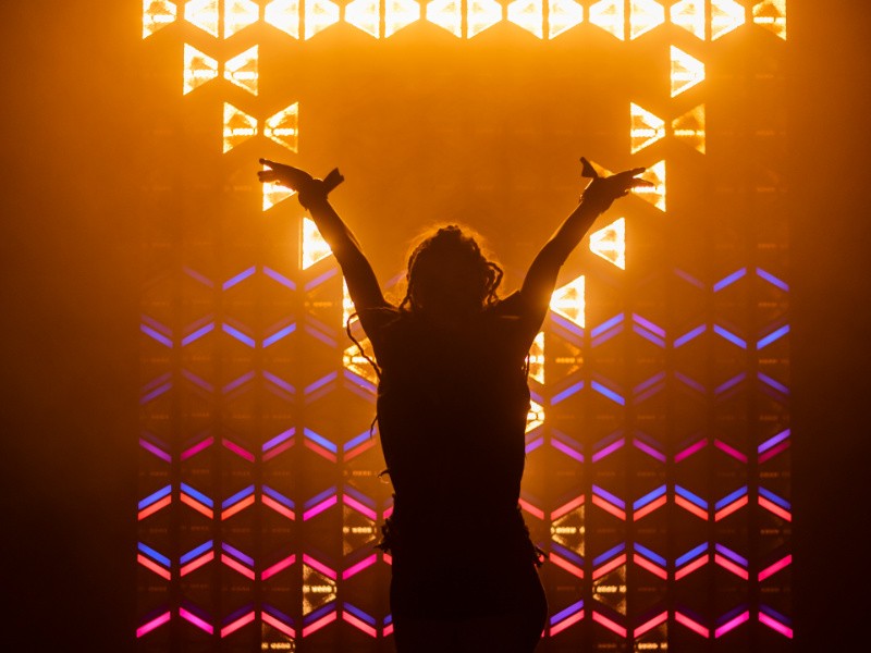 S-TRIBE - wall of fixtures behind a performer
